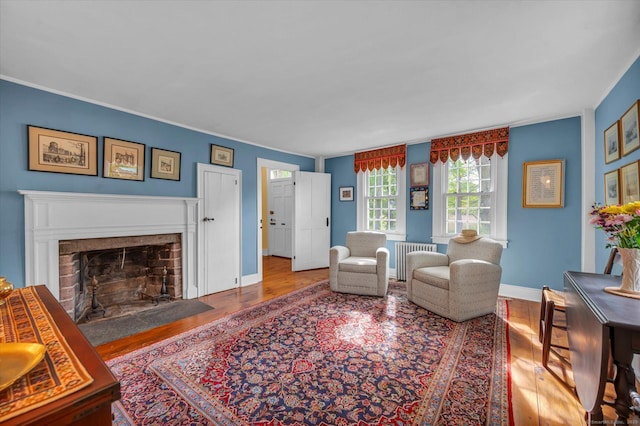 living area with wood finished floors, a fireplace, radiator heating unit, and baseboards