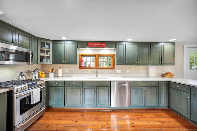 kitchen featuring green cabinets, appliances with stainless steel finishes, a sink, light countertops, and recessed lighting