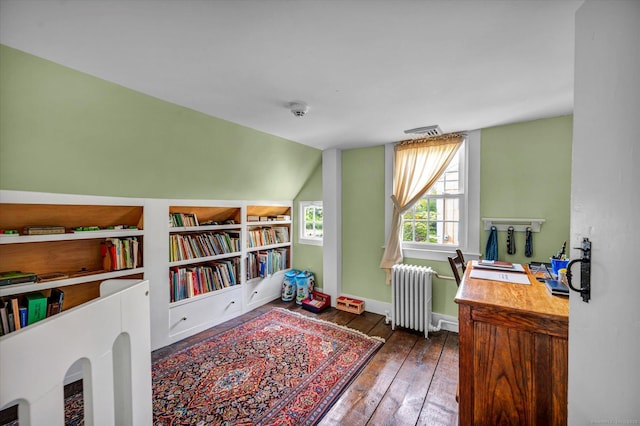 office area featuring radiator, hardwood / wood-style flooring, vaulted ceiling, and baseboards