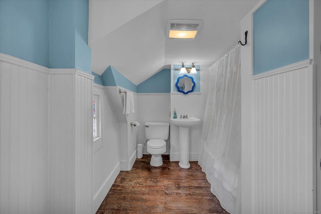 bathroom with toilet, wainscoting, wood finished floors, and lofted ceiling