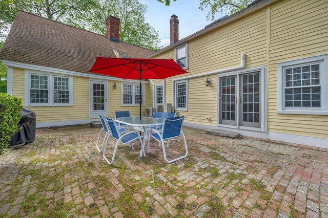 back of house with a patio, outdoor dining area, and a chimney