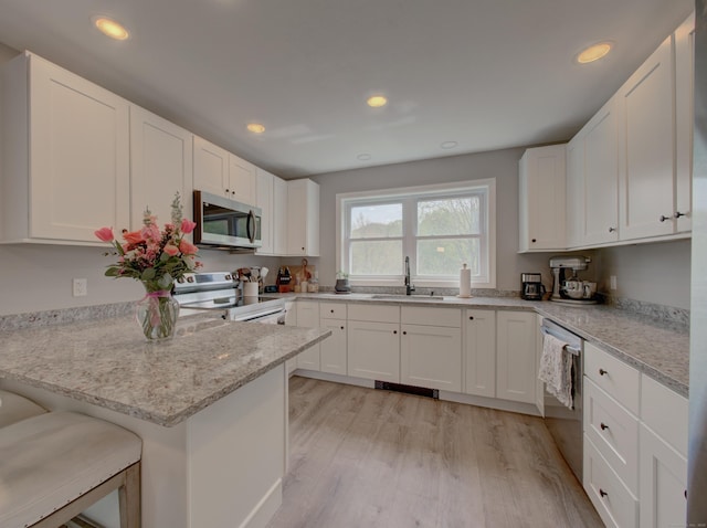 1026 Rte 171, Woodstock, CT 06281 - kitchen with appliances with stainless steel finishes, a sink, light wood-style floors, a peninsula, and white cabinets