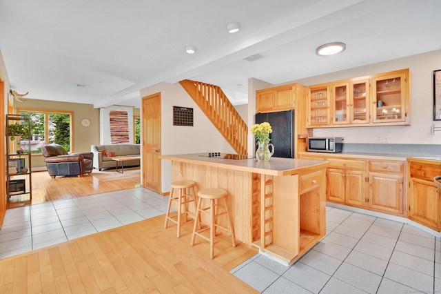 33 Erdoni Rd, Columbia, CT 06237 - kitchen with black fridge, stainless steel microwave, light brown cabinetry, a breakfast bar area, and glass insert cabinets