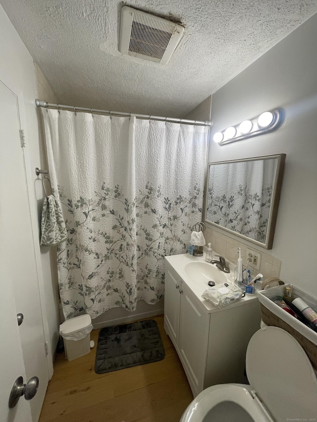 1315 Hamilton Ave, Waterbury, CT 06706 - full bathroom with wood finished floors, a textured ceiling, toilet, vanity, and shower / tub combo