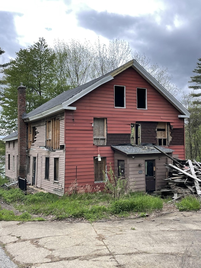 view of side of home with a chimney and central air condition unit