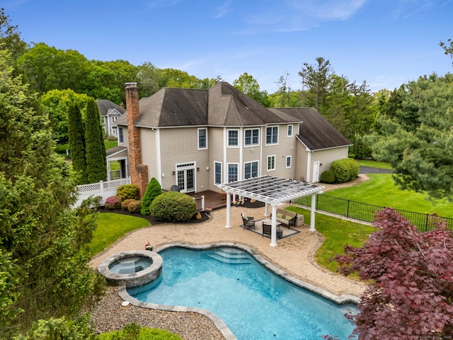 rear view of property featuring a patio, a chimney, and a pool with connected hot tub
