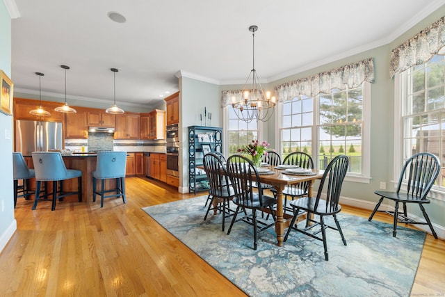 dining area with a chandelier, light wood-type flooring, ornamental molding, and baseboards