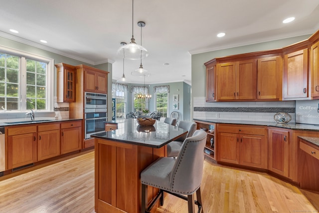 kitchen featuring a sink, brown cabinetry, ornamental molding, a breakfast bar area, and decorative backsplash