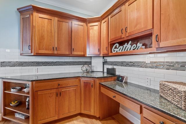 kitchen with open shelves, decorative backsplash, dark stone counters, crown molding, and brown cabinets