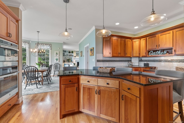kitchen featuring ornamental molding, backsplash, a chandelier, light wood-type flooring, and pendant lighting