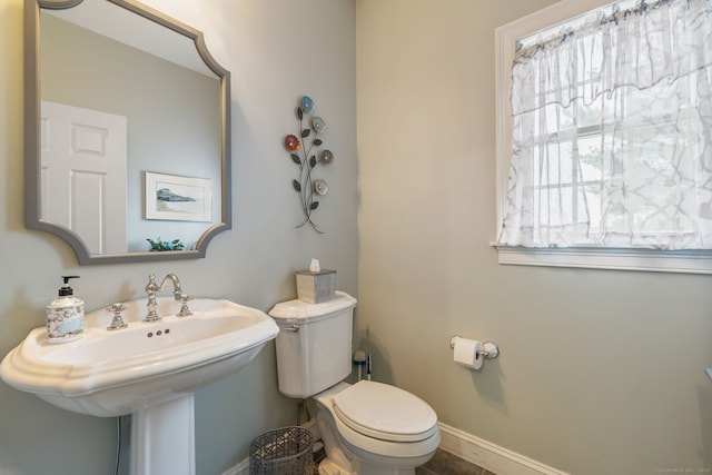 bathroom with toilet, baseboards, and a sink