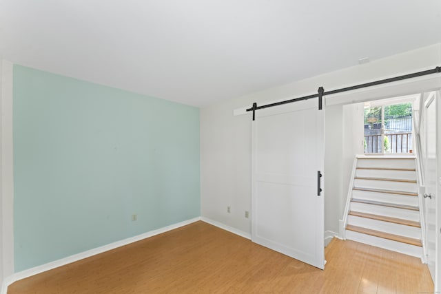 101 Grove St Apt 19, Stamford, CT 06901 - unfurnished bedroom with a barn door, light wood-type flooring, and baseboards