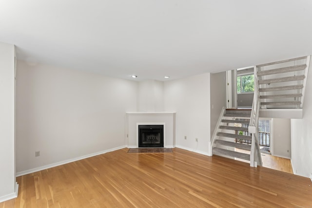 101 Grove St Apt 19, Stamford, CT 06901 - unfurnished living room with light wood-type flooring, stairs, a fireplace with flush hearth, baseboards, and recessed lighting