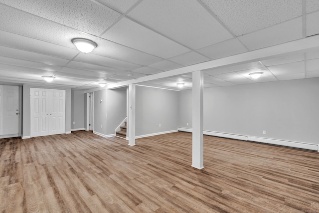 6 Marbil Rd, Danbury, CT 06811 - finished below grade area with wood finished floors, stairway, baseboards, a drop ceiling, and a baseboard radiator