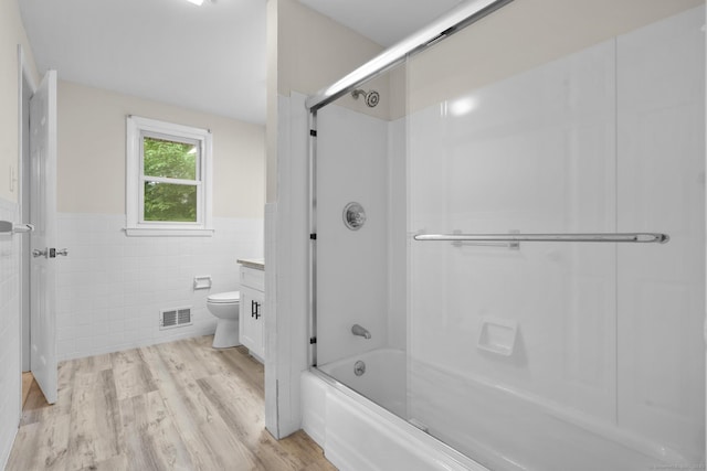 110 Hesse Rd, Hamden, CT 06517 - bathroom with tile walls, a wainscoted wall, toilet, bath / shower combo with glass door, and wood finished floors