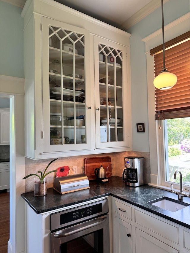 27 Church St, Groton, CT 06340 - kitchen featuring oven, glass insert cabinets, white cabinets, backsplash, and ornamental molding