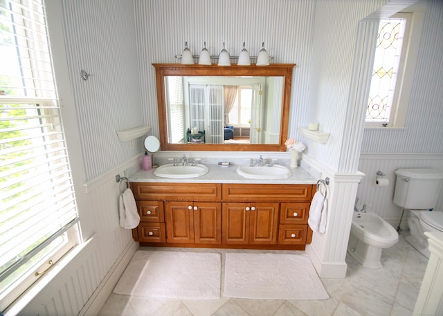 27 Church St, Groton, CT 06340 - bathroom featuring a bidet, wallpapered walls, double vanity, a wainscoted wall, and tile patterned floors