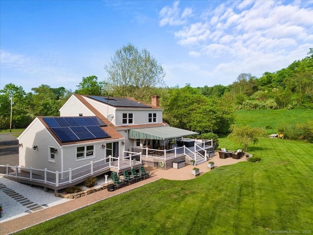 299 W Flat Hill Rd, Southbury, CT 06488 - rear view of property with a patio area, a deck, roof mounted solar panels, a chimney, and a lawn