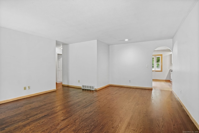 unfurnished room with arched walkways, wood finished floors, baseboards, and recessed lighting