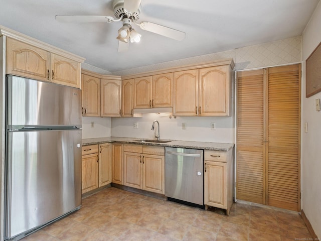 kitchen with stainless steel appliances, light brown cabinets, a sink, and light stone countertops