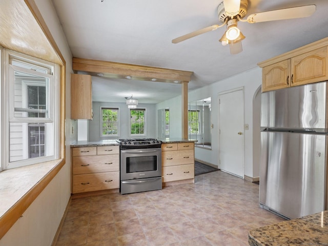 kitchen with stainless steel appliances, light brown cabinetry, baseboards, and a ceiling fan