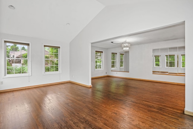 empty room with healthy amount of natural light, wood finished floors, a chandelier, and high vaulted ceiling