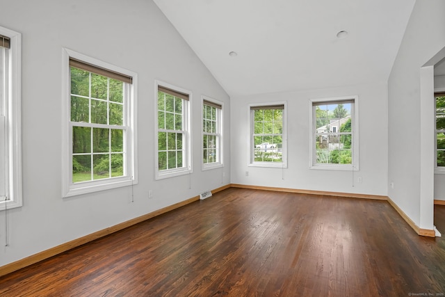 spare room featuring lofted ceiling, healthy amount of natural light, dark wood-style flooring, and baseboards