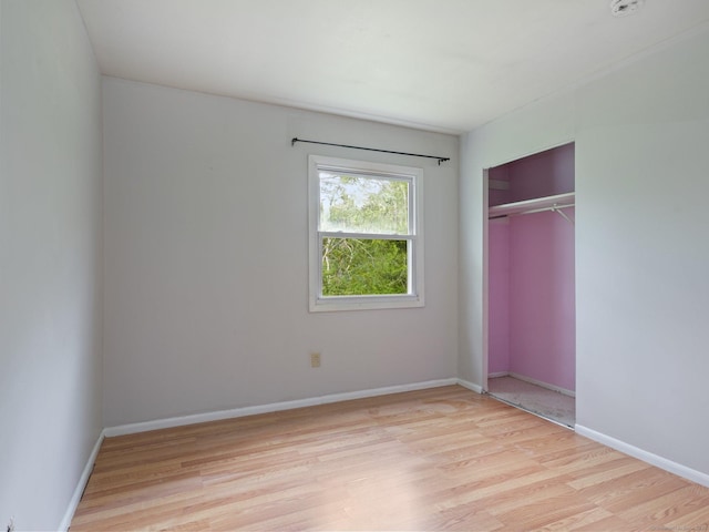 unfurnished bedroom featuring light wood-type flooring, a closet, and baseboards