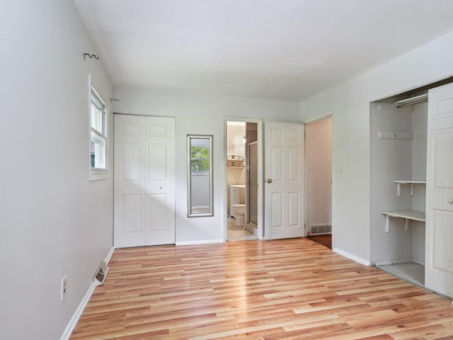 unfurnished bedroom with light wood finished floors, baseboards, and ensuite bath