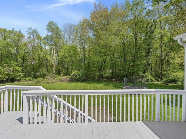 wooden terrace with a trampoline and a yard