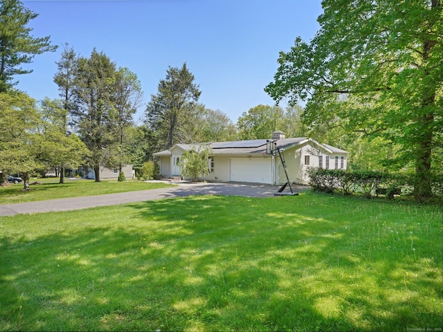 ranch-style home featuring a garage, asphalt driveway, roof mounted solar panels, and a front lawn