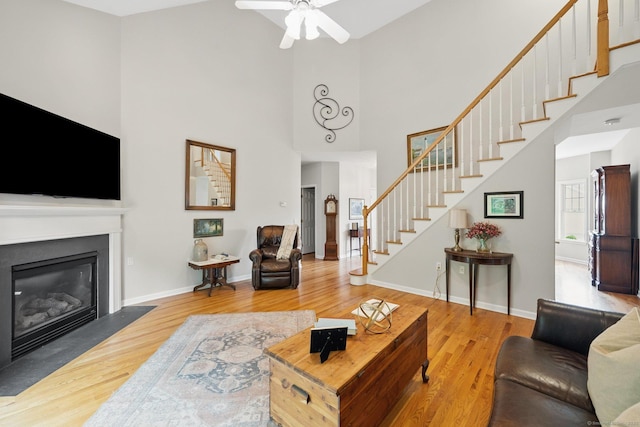 107 Chestnut Hill Rd Unit 107, Portland, CT 06480 - living area with stairway, wood finished floors, a towering ceiling, a glass covered fireplace, and a ceiling fan