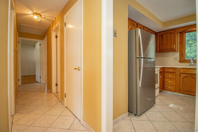 123 Jeffrey Ln, Newington, CT 06111 - kitchen with freestanding refrigerator, light tile patterned floors, and brown cabinetry