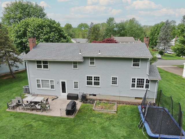 207 Pheasant Dr, Rocky Hill, CT 06067 - rear view of house with a patio area, central AC unit, a trampoline, a chimney, and a lawn