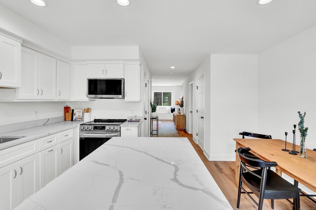 33 Main St Unit 1, Meriden, CT 06451 - kitchen featuring appliances with stainless steel finishes, light wood-style flooring, recessed lighting, white cabinetry, and light stone counters
