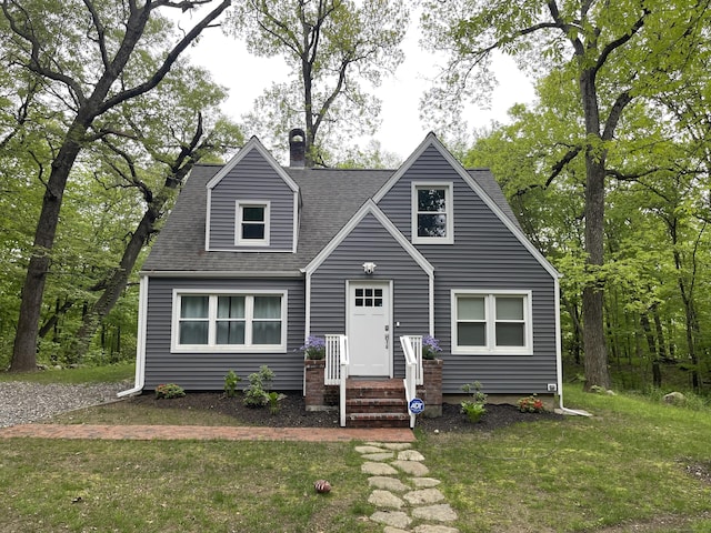 view of front of house with a front lawn, roof with shingles, and a chimney
