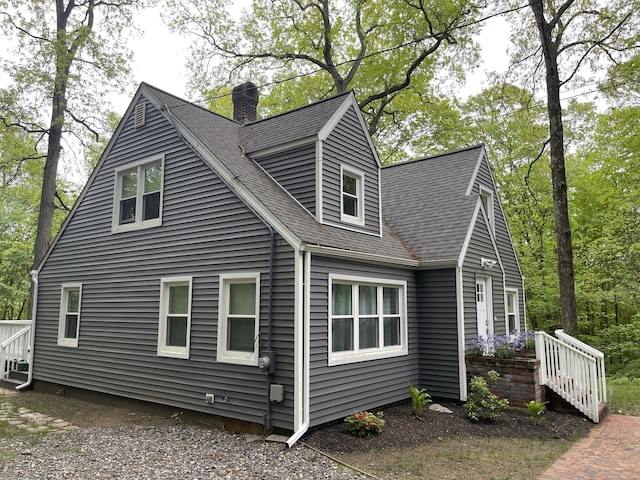 view of side of property with a chimney and roof with shingles