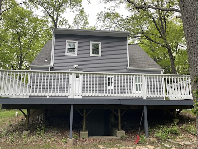 back of house featuring roof with shingles and a deck
