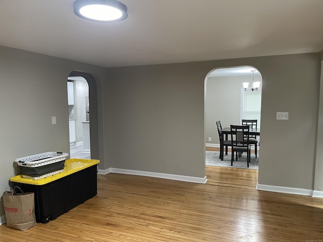 office area with arched walkways, baseboards, light wood-style floors, and a chandelier