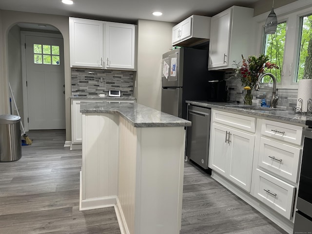 kitchen with stainless steel dishwasher, a sink, arched walkways, tasteful backsplash, and recessed lighting