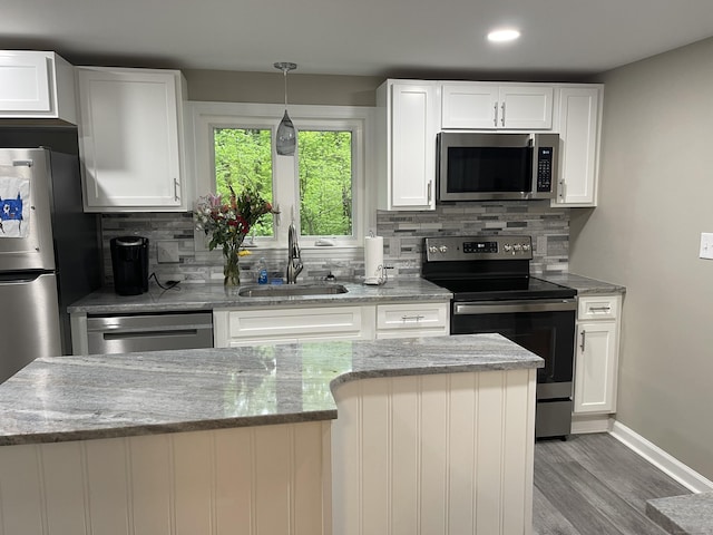 kitchen with stainless steel appliances, a sink, wood finished floors, tasteful backsplash, and recessed lighting