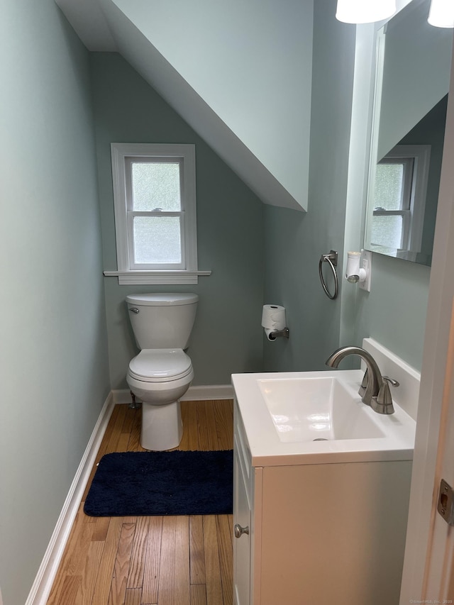 bathroom featuring toilet, wood finished floors, plenty of natural light, vanity, and vaulted ceiling