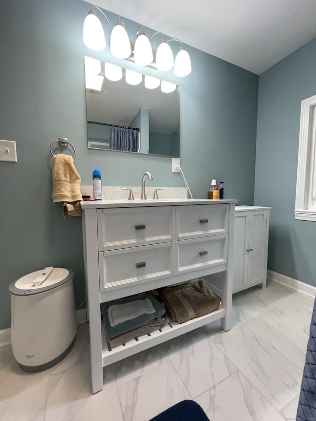 full bathroom with marble finish floors, vanity, baseboards, and curtained shower