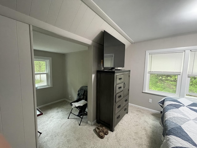 bedroom featuring light carpet, vaulted ceiling, and baseboards