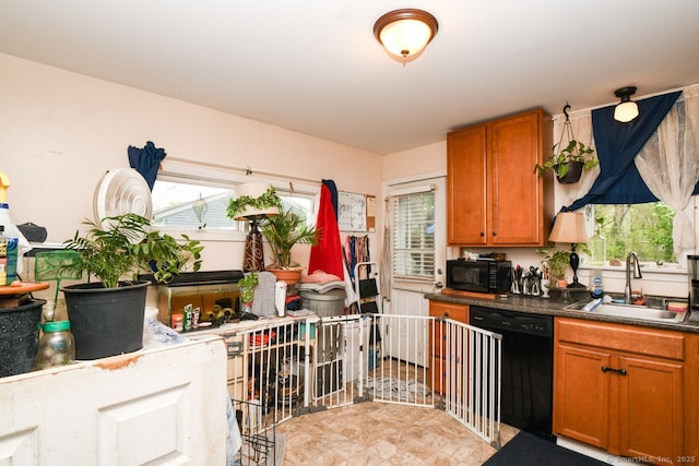 kitchen with black appliances, a sink, brown cabinetry, and dark countertops
