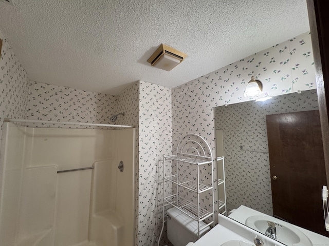 227 Twin Lakes Rd Apt C, North Branford, CT 06471 - bathroom with wallpapered walls, a textured ceiling, walk in shower, toilet, and vanity