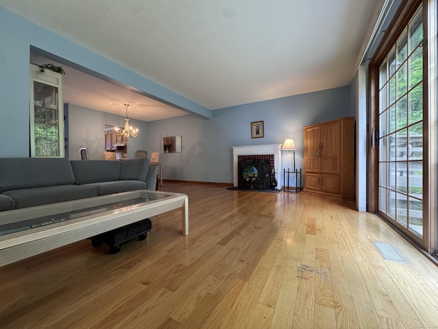 227 Twin Lakes Rd Apt C, North Branford, CT 06471 - living area featuring a chandelier, light wood-style floors, a fireplace, and baseboards