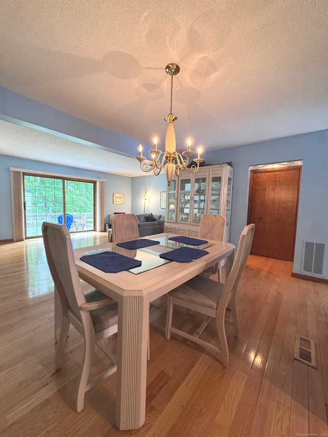 227 Twin Lakes Rd Apt C, North Branford, CT 06471 - dining space with a chandelier, a textured ceiling, and light wood finished floors