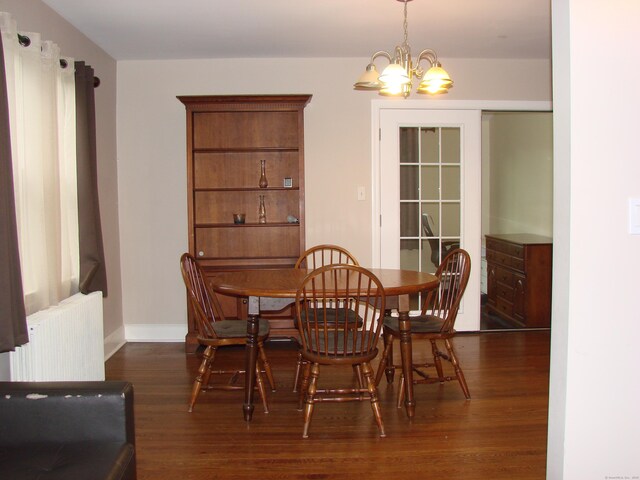 566 Savoy St, Bridgeport, CT 06606 - dining area with radiator heating unit, dark wood-type flooring, a chandelier, and baseboards