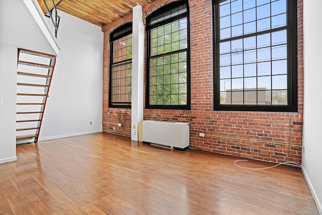 25 Grand St Apt 102, Norwalk, CT 06851 - unfurnished room with radiator, wood finished floors, wood ceiling, brick wall, and baseboards